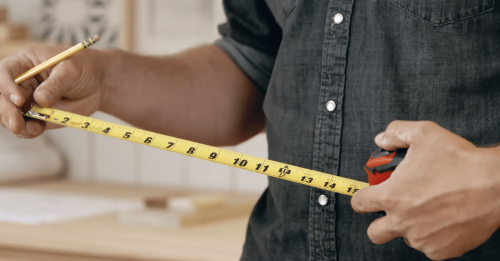 Professional preparing to take measurements for made to measure furniture production using a tape measure. 